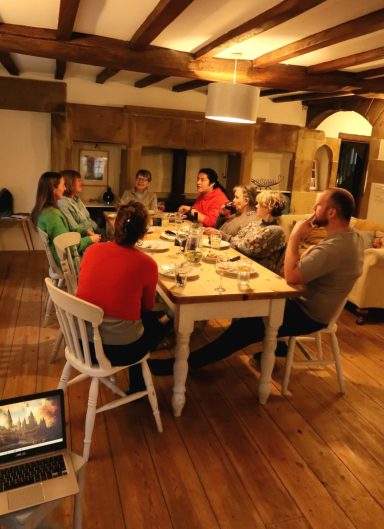 A group of people seated around a dining table in a rustic room.
