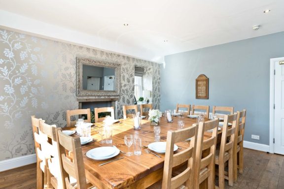 Bright dining room with a large wooden table, chairs, and decorative walls.