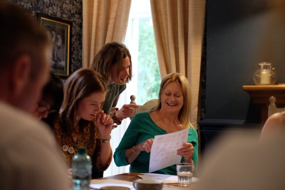 Group of people engaged in a discussion, reviewing papers with smiles and focused expressions.