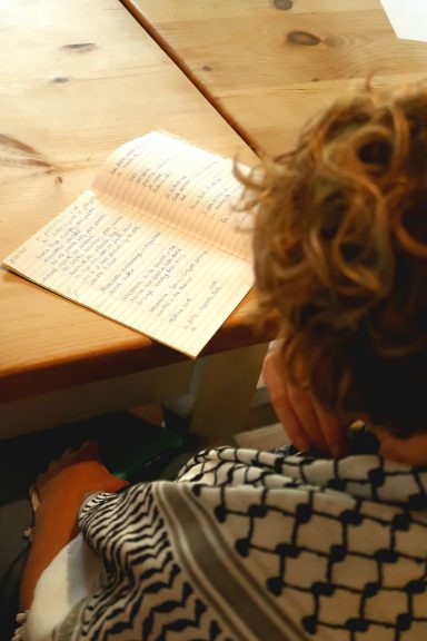 A person with curly hair reading a document while sitting at a wooden table.