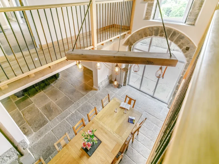 Speak Spanish in the UK Spacious modern dining area with wooden table and large windows, featuring elegant decor.