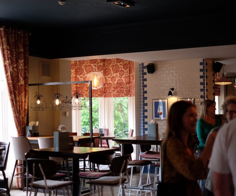 Table set for breakfast with croissants, bowls, juice, and a vase of tulips.