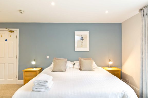A modern bedroom with a double bed, two bedside tables, and light blue walls.