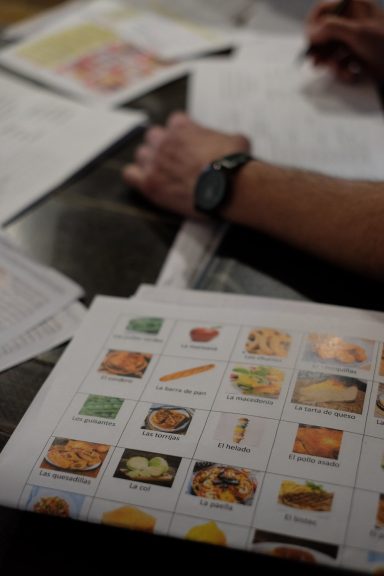 Hands working on papers with images of food items and other documents.