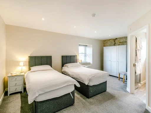Two twin beds with white linens in a light, neutral bedroom setting.