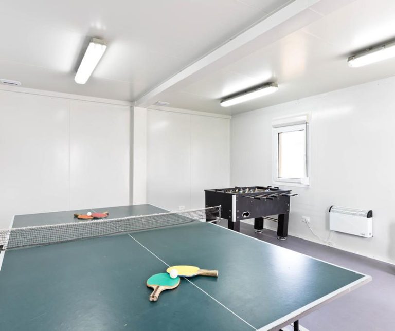Table tennis and foosball tables in a bright, minimalistic room.