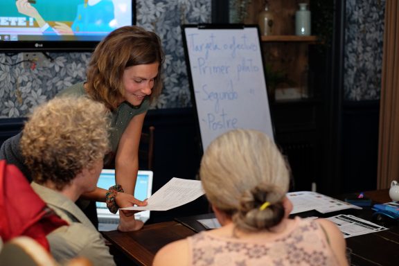 A woman engages with two older individuals at a table during a group discussion.