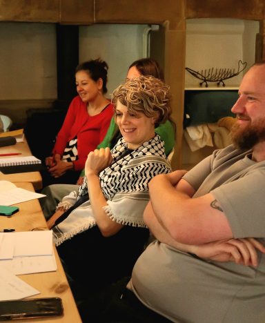 A group of people engaged in discussion at a table, displaying smiles and relaxed postures.